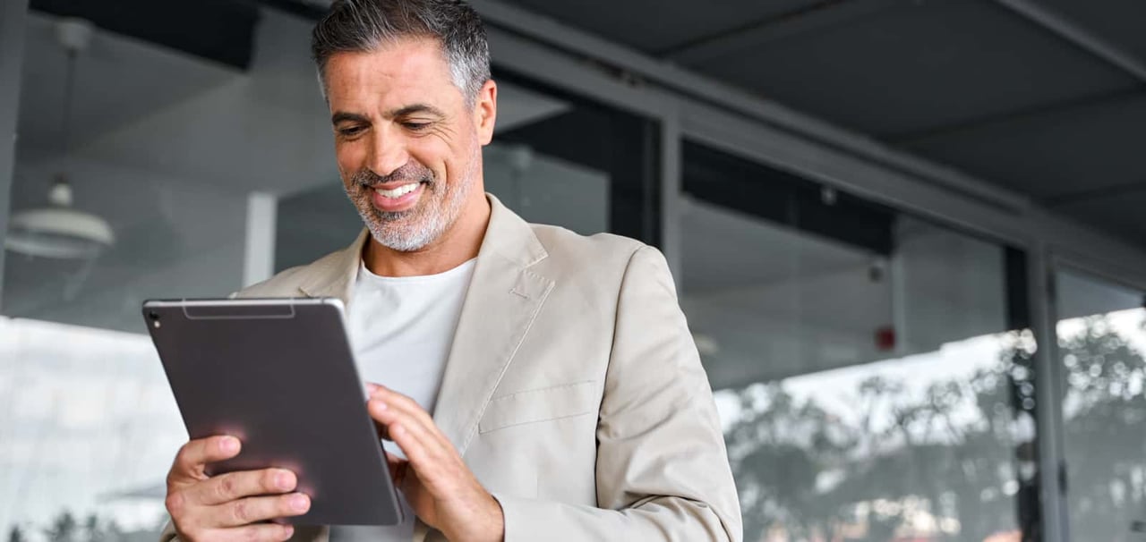 Man smiling and holding a tablet.